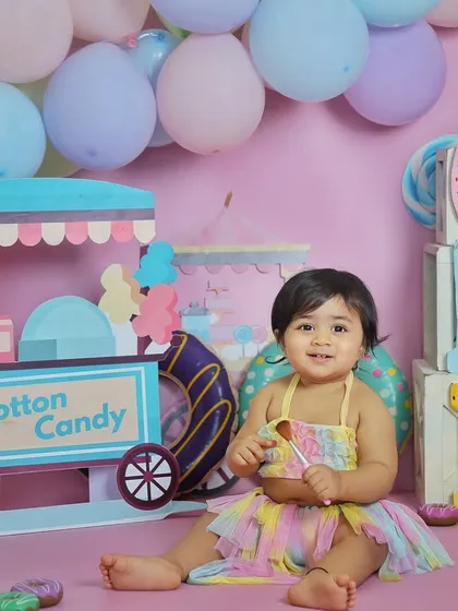 A sweet portrait from a candyland-themed first birthday shoot. The pastel colors, donut props, and cotton candy stand create a whimsical and fun atmosphere.
