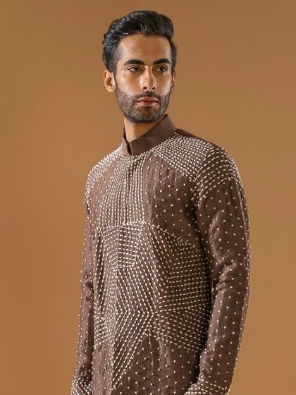 A closer, angled view of the brown kurta with geometric threadwork, highlighting the texture and detail of the craftsmanship.