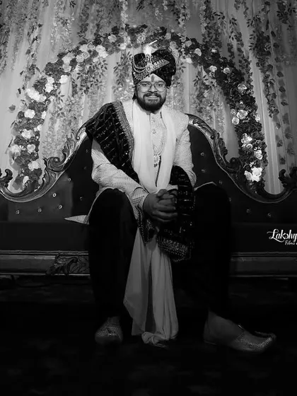 A timeless black and white portrait of the groom. This classic style emphasizes his expression and the rich textures of his wedding attire, creating a powerful and elegant image.