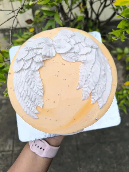 I was skeptical about creating freehand wings, but I'm so glad I did. The outcome was phenomenal. This angel wing cake features intricately textured buttercream wings on a soft peach-colored base.