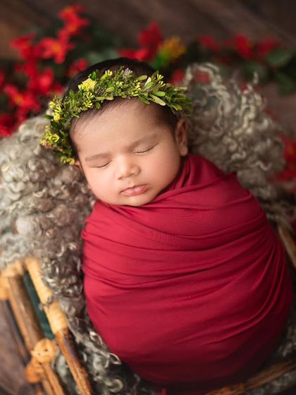 This baby is wrapped snugly in a bold red, nestled in a basket with a festive floral crown. Props are a great way to incorporate vibrant colors.