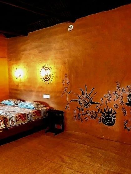 The interior of a rustic mud house at the Vattavada camp, featuring unique tribal art on the walls for an authentic feel.