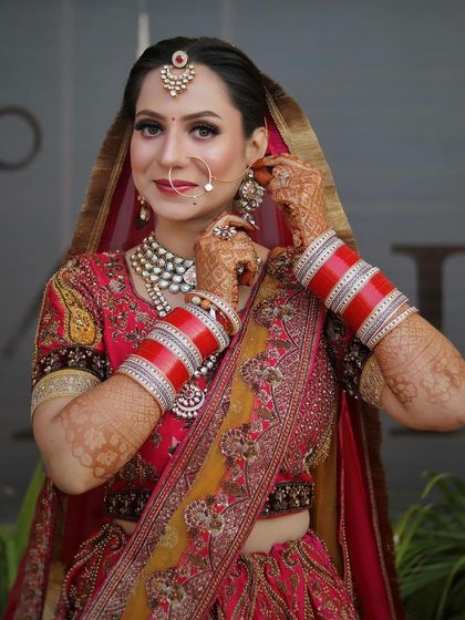 A candid moment of the bride adjusting her earring, giving a great view of her profile and the intricate details of her look.