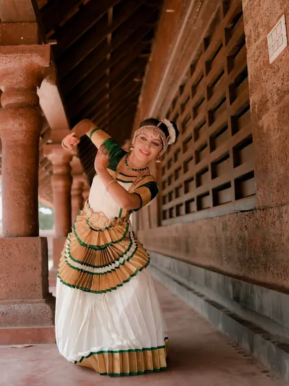 This shot captures a dancer in mid-pose, showcasing the dynamic movement and expressive nature of Mohiniyattam. The architectural lines of the corridor frame her beautifully.