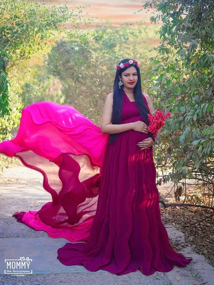 A confident and beautiful pose with a flowing gown. The movement of the fabric and the natural background create a stunning and powerful outdoor maternity photograph.