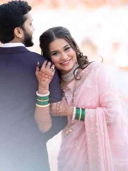 A sweet, romantic moment from their reception. Her makeup is soft and pretty in a pink saree, perfect for the evening's celebration.
