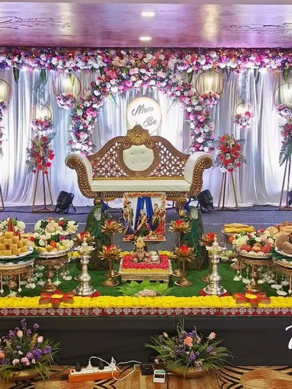 A full stage view of a traditional baby shower plate decoration. The setup includes two 'Pattada Gombe' dolls at each end, symbolizing blessings for the family's growing lineage.