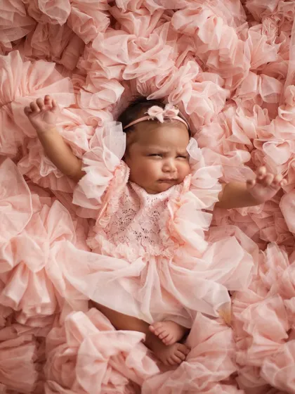 A big stretch! Even when they're not perfectly posed, these natural movements make for such adorable and authentic photographs. This little girl is waking up from her nap in a sea of pink ruffles.