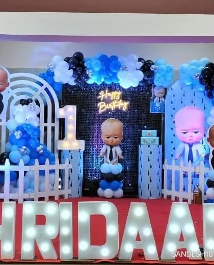 A large-scale "Boss Baby" themed stage with multiple character cutouts, a sequin backdrop, and light-up marquee letters spelling the name "HRIDAAN."
