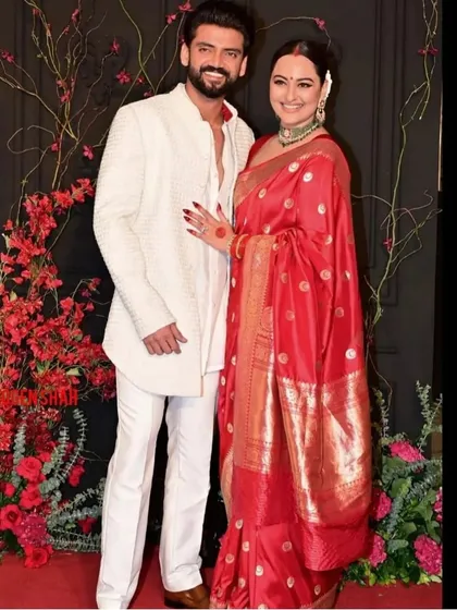 For their reception, we created a stunning photo backdrop of red florals against a dark, moody canvas, allowing the couple's vibrant and elegant attire to truly shine.