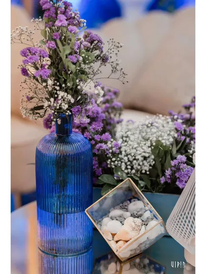 A detail shot of a table centerpiece, combining purple flowers with a blue textured vase and a box of white pebbles. This shows how I carry the color palette through even the smallest details.