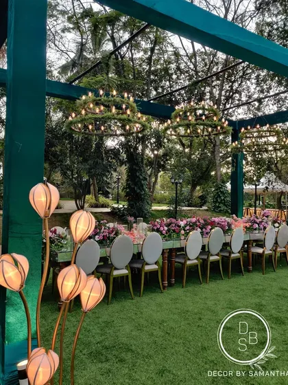 An outdoor setting offers a beautiful canvas. For this lakeside reception, we designed a long, mirrored dining table adorned with lush floral runners and surrounded by elegant seating, creating a serene and magical dining experience under twinkling lights.
