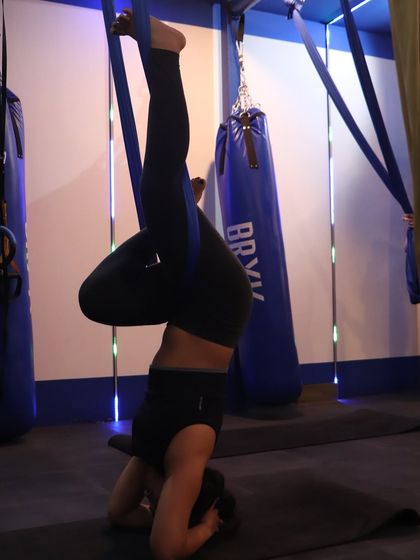Another powerful shot of Anushka in an aerial headstand, using the hammock for support. This demonstrates the core strength she developed through consistent practice.