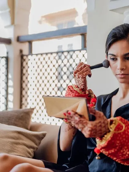 The bride begins her makeup, getting ready for her big day with the beautiful Rajasthani landscape visible from her window.
