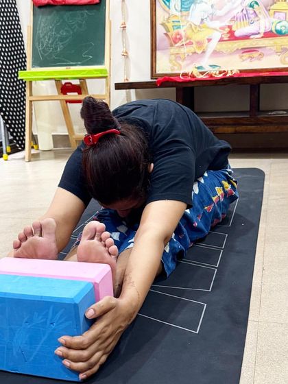 A student using blocks in Paschimottanasana (Seated Forward Bend) to deepen the stretch and maintain a long spine, a smart way to use props for progress.