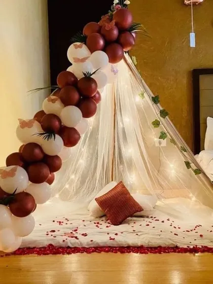 We can bring the cozy cabana experience indoors, as shown in this bedroom canopy decoration. A simple teepee structure with fairy lights, a balloon garland, and rose petals transforms the room into a romantic retreat.