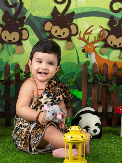 This little one is having a great time playing with the animal props in our jungle setup. The leopard print outfit is the perfect touch.