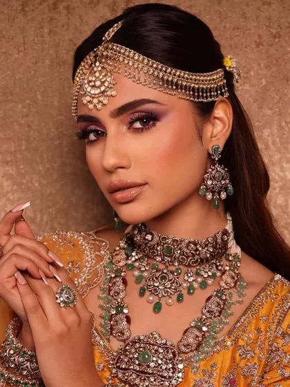 A detailed shot of the purple smokey eye look, showing the intricate jewellery and the flawless application of the makeup. The nails are also perfectly manicured, a small but important detail.