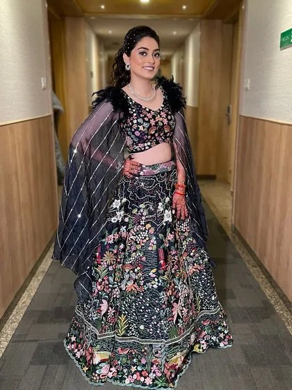 A full-length view of the bride, ready for her Sangeet. The entire look, from the feathered blouse to the sparkling makeup, is pure elegance.