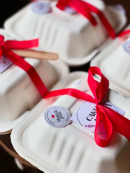 A close-up of my bento cake packaging. I add a "thank you" sticker and a branded sticker to each box, along with a bright red ribbon for a festive touch.
