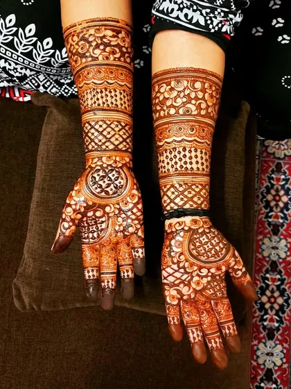 A classic bridal design featuring bold circles on the palm, surrounded by delicate, detailed work extending up the arm. This style is timeless and always looks stunning.
