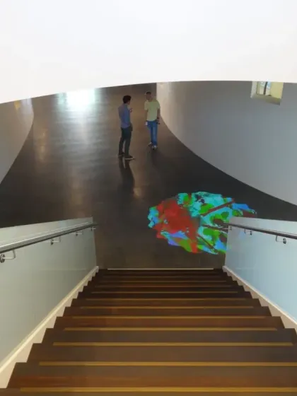 Looking down the main staircase at Virchow 16, the 'Amorphous Color Rain' art projection creates a pool of color at the base. The art is integrated into the primary circulation path, making it a part of everyone's daily experience.