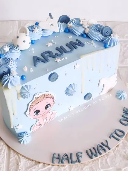 Halfway to one! This sweet half-birthday cake in baby blue is decorated with cute buttons, stars, and a white chocolate drip, celebrating six months of happiness.