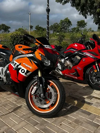 A pair of Honda superbikes, one in the iconic Repsol racing livery, parked and gleaming in the sun, representing the passion of the biking community.