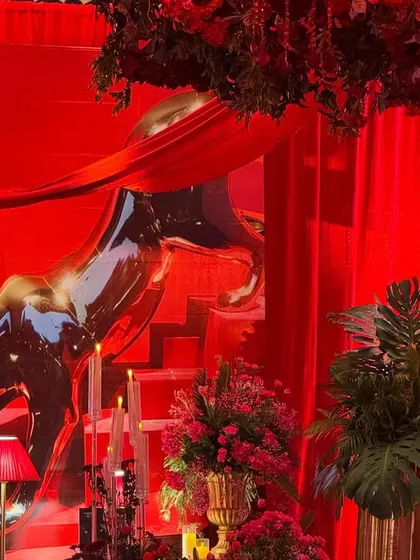 The iconic Cartier panther, reimagined as a metallic sculpture, appears to leap across the stage. This statement piece, combined with dramatic red draping and lighting, became a central focus of the event design.