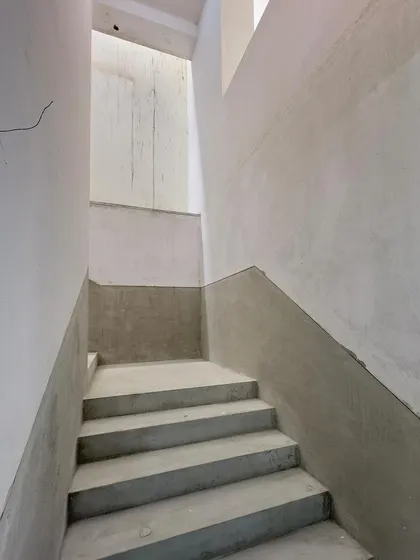 A concrete staircase in its raw state, a sculptural form connecting different levels of a building in progress.
