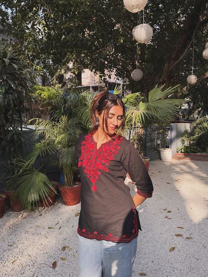 A cute, playful pose in the same black and red kurti, looking down with a smile.