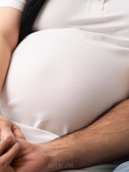 A close-up detail shot, focusing on the hands and the baby bump. These small, intimate details often tell the biggest stories of love and connection.