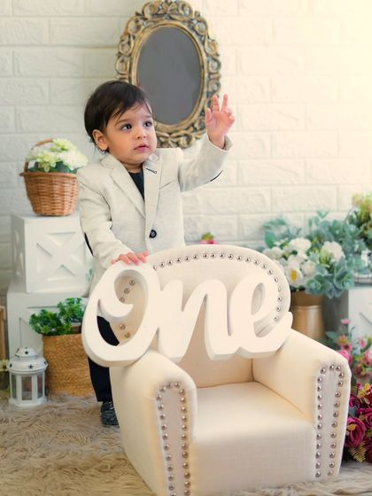A stylish little man celebrating his first birthday. He looks so confident and happy standing by his miniature armchair.
