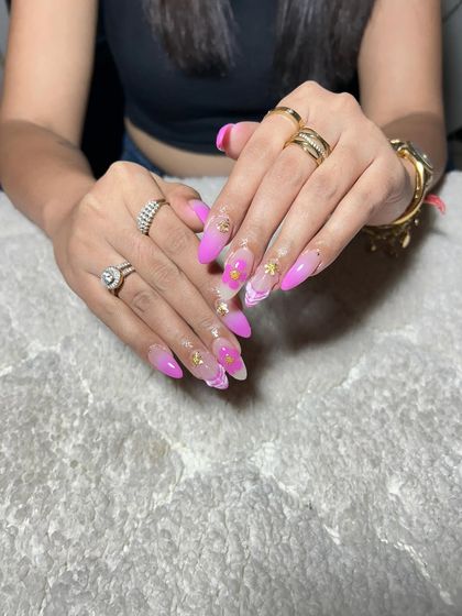 A bright pink and white ombre set with a marble effect and gold flakes. This design combines multiple trends for a fun and glamorous result.