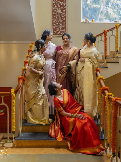 The bride sharing a laugh with her bridesmaids on the stairs, a candid moment of friendship before the wedding chaos begins.
