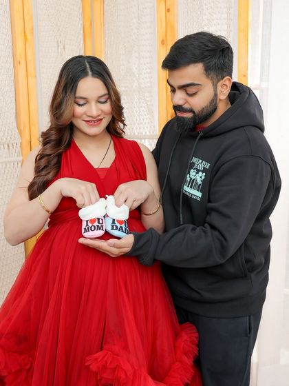The couple shares a look as they present the tiny baby shoes, a symbol of the new life they are eagerly awaiting.