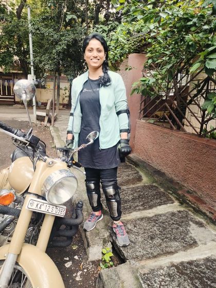 A graduate stands proudly next to her bike, fully kitted out in safety gear. She's not just a rider; she's a safe and responsible one.