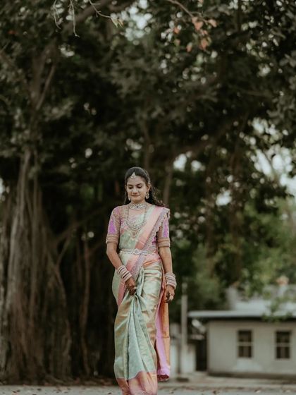 The bride walking gracefully under a large banyan tree, a picture of timeless elegance.