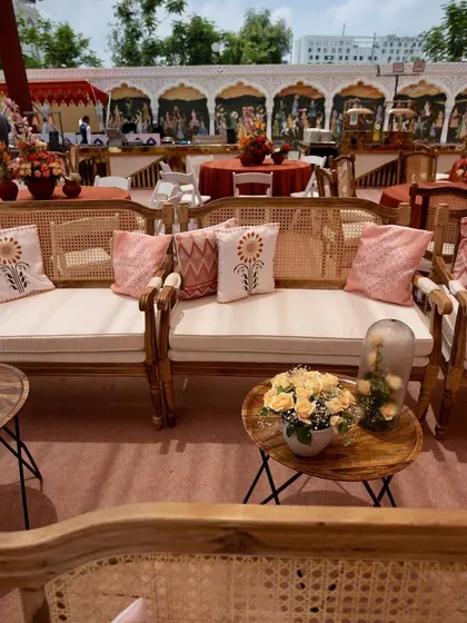An earthy and elegant Bhaat ceremony. The decor features natural wood furniture, printed cushions, and beautiful floral arrangements.