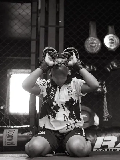 A powerful black and white photo of a young fighter inside the cage, focused and ready.