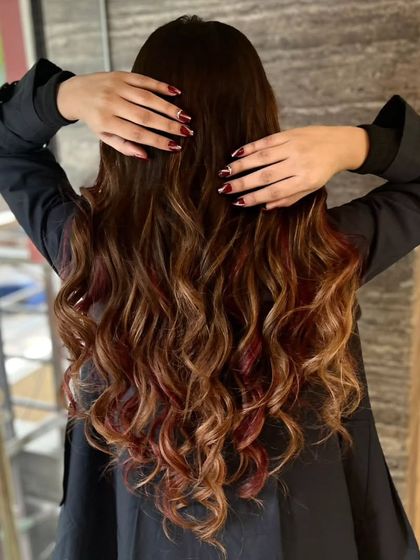 A stunning example of our hair coloring work. This client got a beautiful balayage with shades of brown and hints of red, styled into perfect waves.