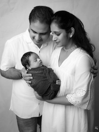 A quiet moment between parents and their newborn, rendered in classic black and white. This version emphasizes the shapes, textures, and the peaceful mood.