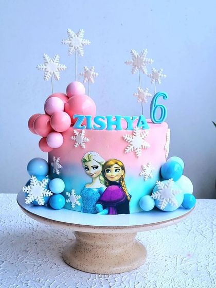 A full view of the pink and blue ombre Frozen cake on its stand.