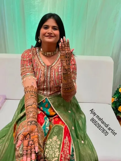 A bride posing happily with her full arm mehndi. The design is intricate and perfectly suited for her wedding attire.