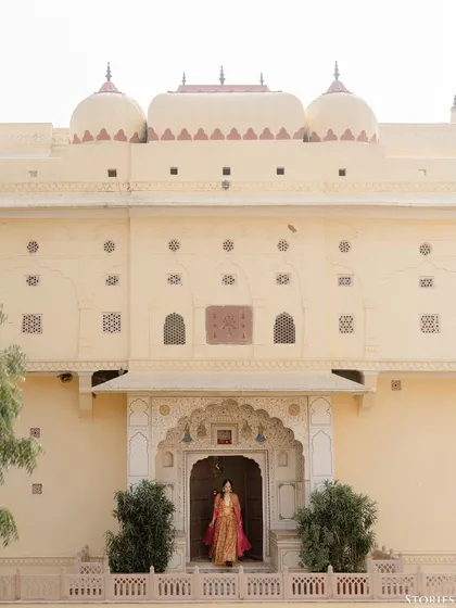A bride framed by the grandeur of a Jaipur palace. This single shot tells a story of heritage, anticipation, and elegance. My approach is to use the environment to elevate the narrative, making you the central character in a magnificent setting.