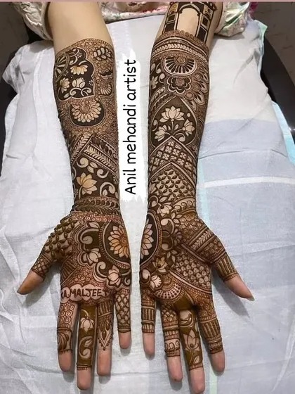 This full-arm bridal mehandi is a masterpiece of detail. It features bands of floral patterns, geometric grids, and a custom name 'AMALJEET' written on the palm.