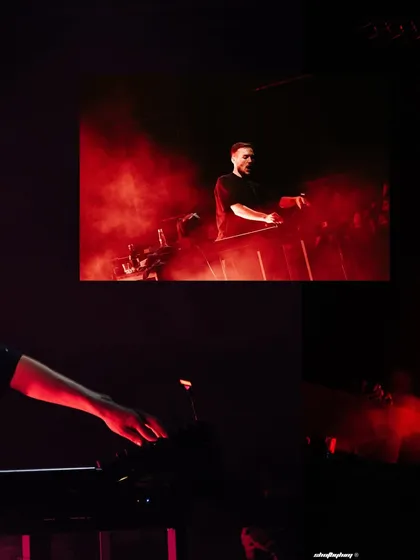 An artistic shot of Ben Böhmer's hands on the keyboard, with his performance on the screen in the background. This highlights the live, instrumental aspect of his show.