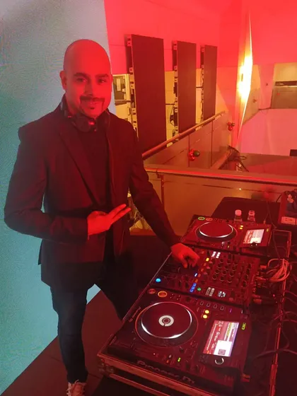 Posing with my Pioneer DJ setup. I use industry-standard equipment to ensure the best possible sound quality and a seamless mixing experience for your event.