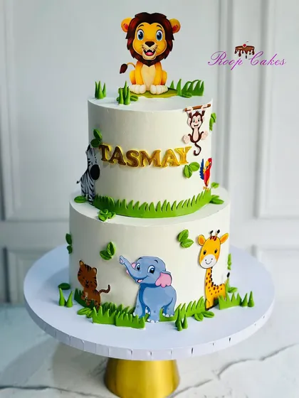 A fun, non-fondant jungle theme cake for a first birthday. This two-tier design features cute, friendly animals like a lion, elephant, and giraffe.