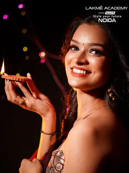 A beautiful Diwali-themed portrait. The model's bright smile and the glowing diya create a warm and festive atmosphere, complemented by her glamorous makeup.